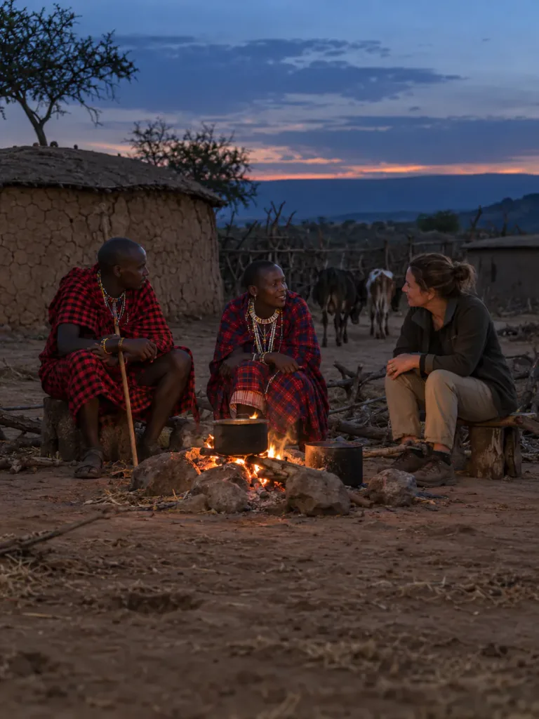 A guest sharing the fire with Maasai hosts at their boma at dusk